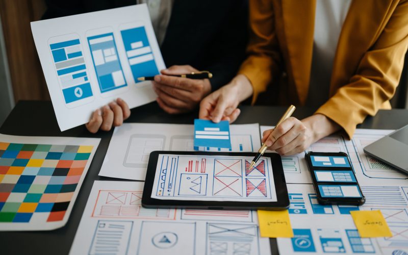 Close up view of UI developer team brainstorming on their project with laptop, smartphone and digital tablet. Creative digital development agency. in office